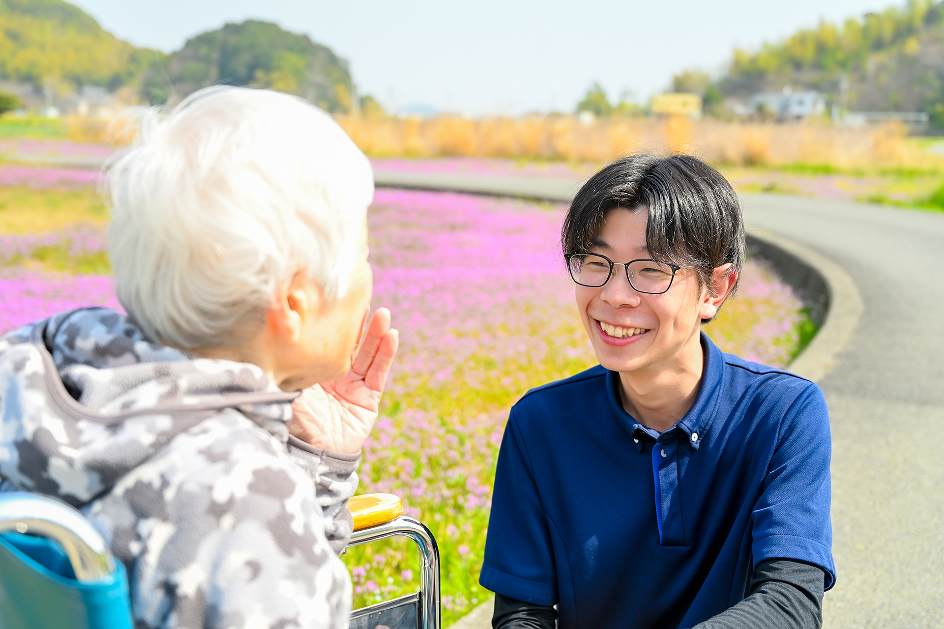 利用者さんと男性職員さん（花畑の背景）